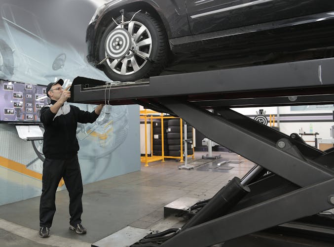 Mechanic inspecting vehicle in a modern auto service garage